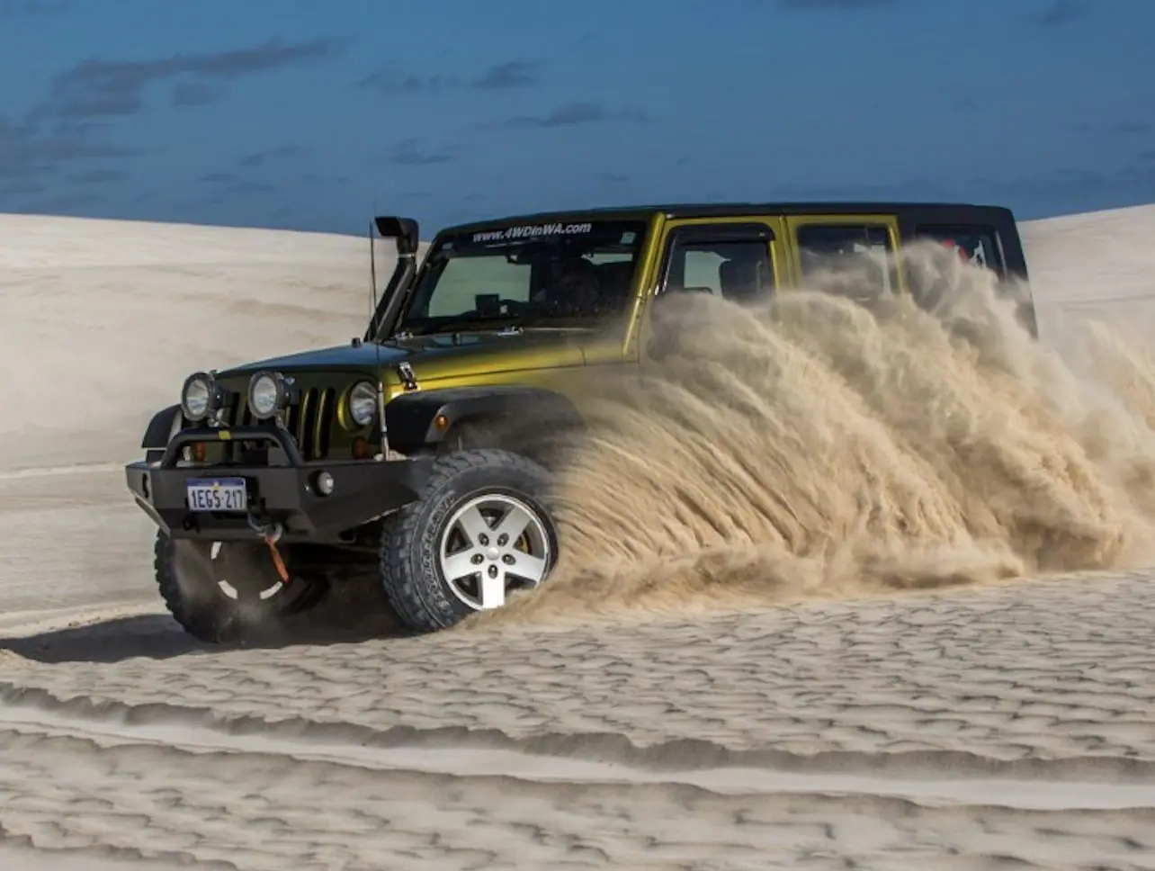 A four-wheel drive cresting a dune on a Dubai desert safari