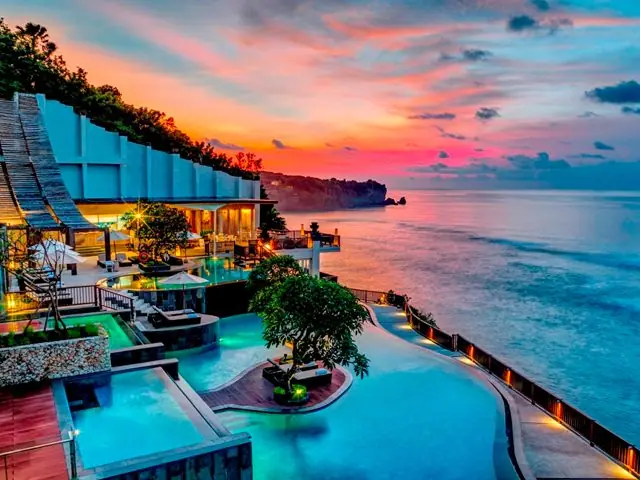A cliff-top pool and terrace above the sea at sunset in Bali