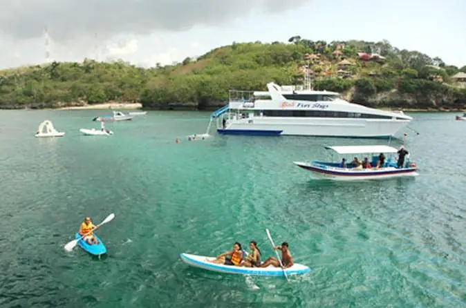A passenger cruiser at anchor off an island, with kayaks alongside